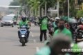 aturan ojol dan aplikator - Ilustrasi pengemudi ojek online (ojol) saat melintas di jalan raya perkotaan.