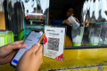 transaksi qris - Ilustrasi warga melakukan pembayaran digital menggunakan transaksi QRIS yang kini semakin mendominasi perekonomian nasional.